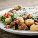 Gnocchi with bacon spinach sauce on a white plate.