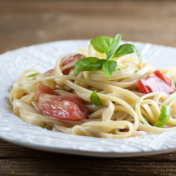 Pasta with brie tomatoes and basil on a plate.