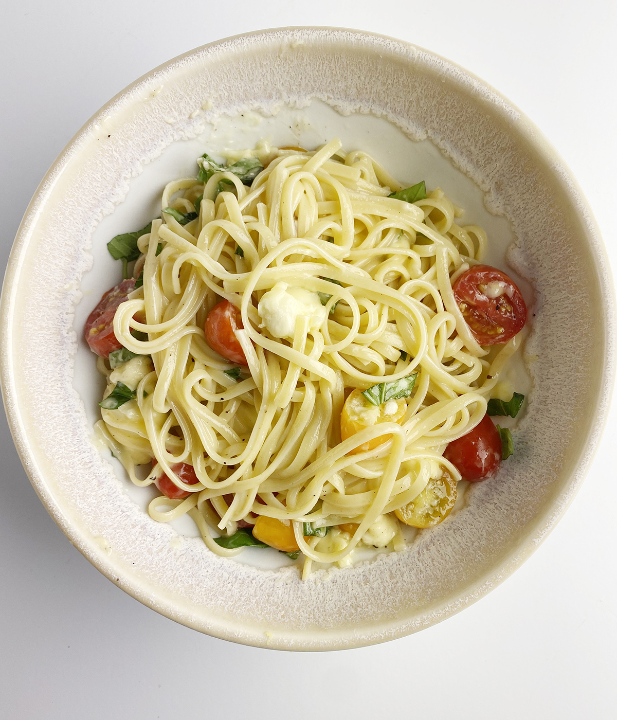 Pasta with tomatoes and brie cheese in a bowl.