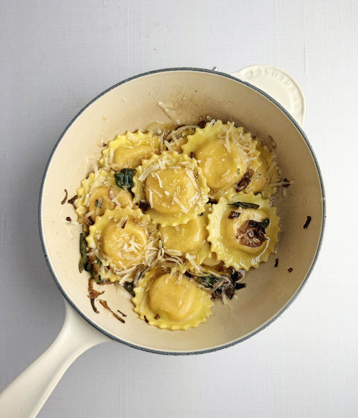 Ravioli with sage butter sauce in a pan.