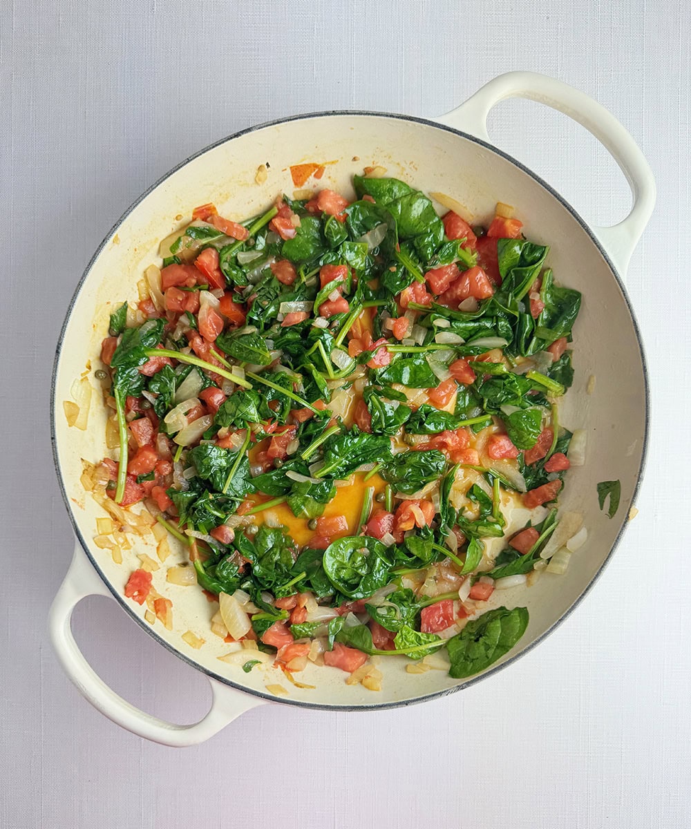 Tomato and spinach cooking in a pan.