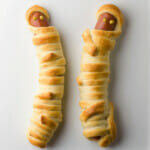Hot dog mummies on a white plate.