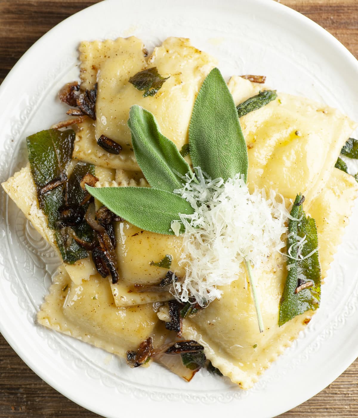 Ravioli with brown butter and sage on a plate.