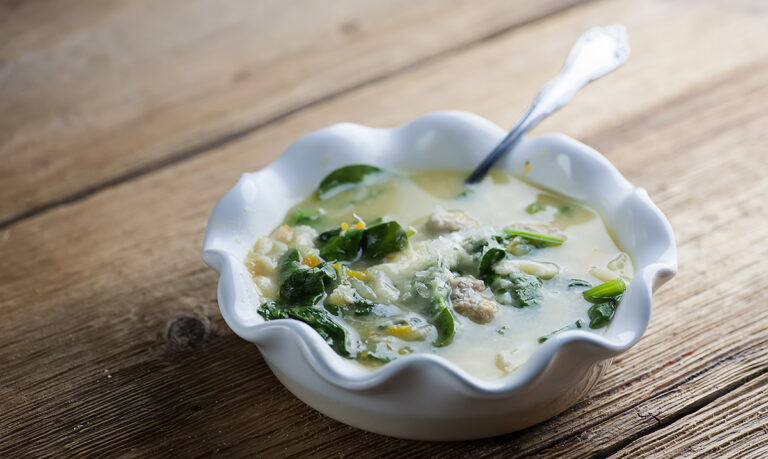 Italian wedding soup in a bowl with a spoon.