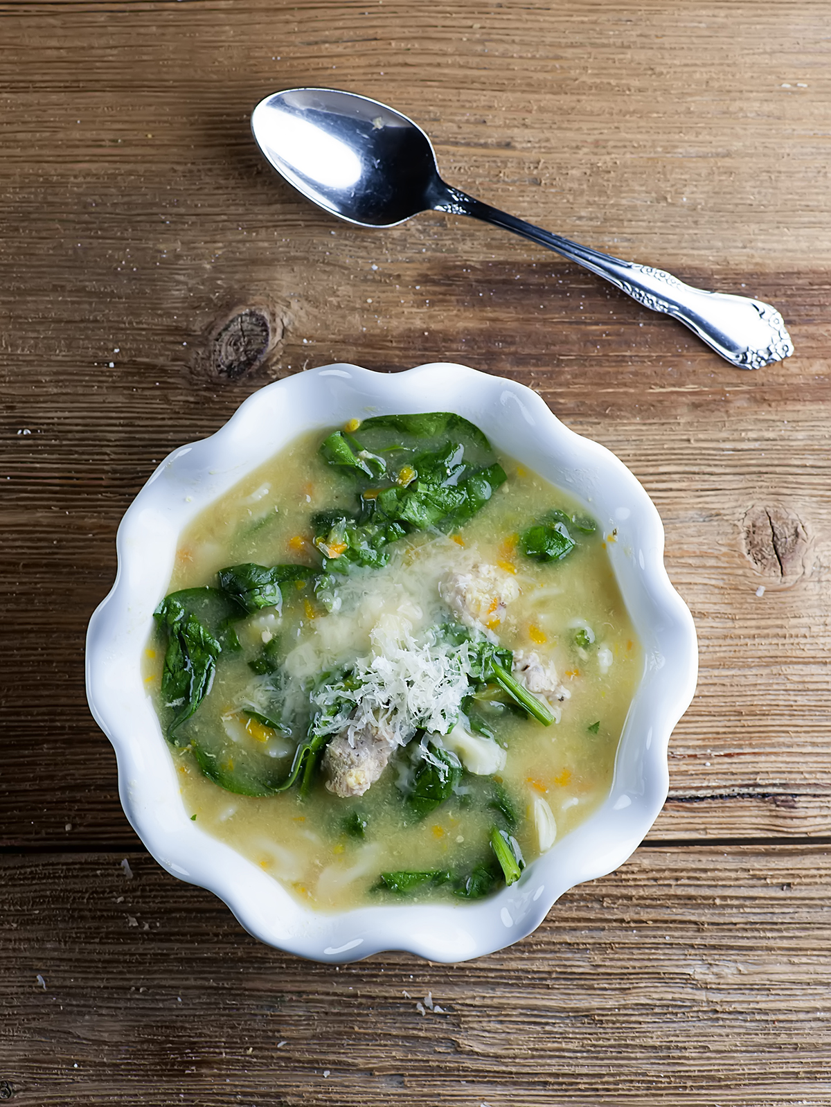 Italian wedding soup on a wooden counter.