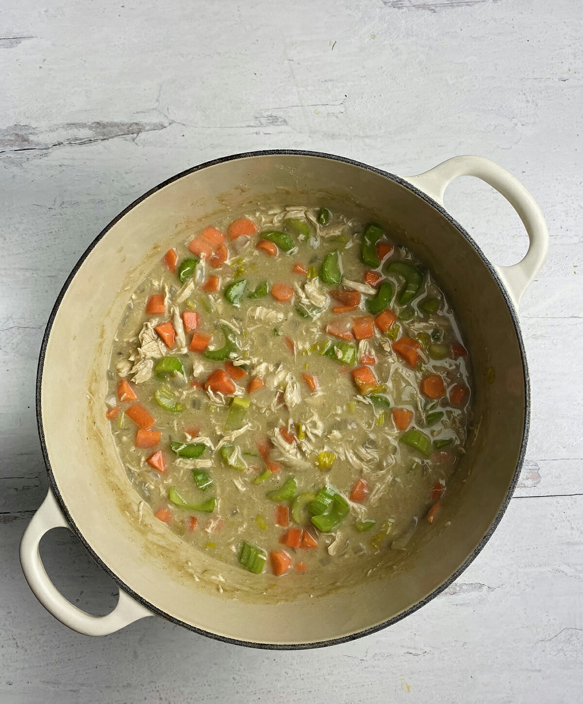 Chicken pot pie vegetables and sauce in a Dutch oven.