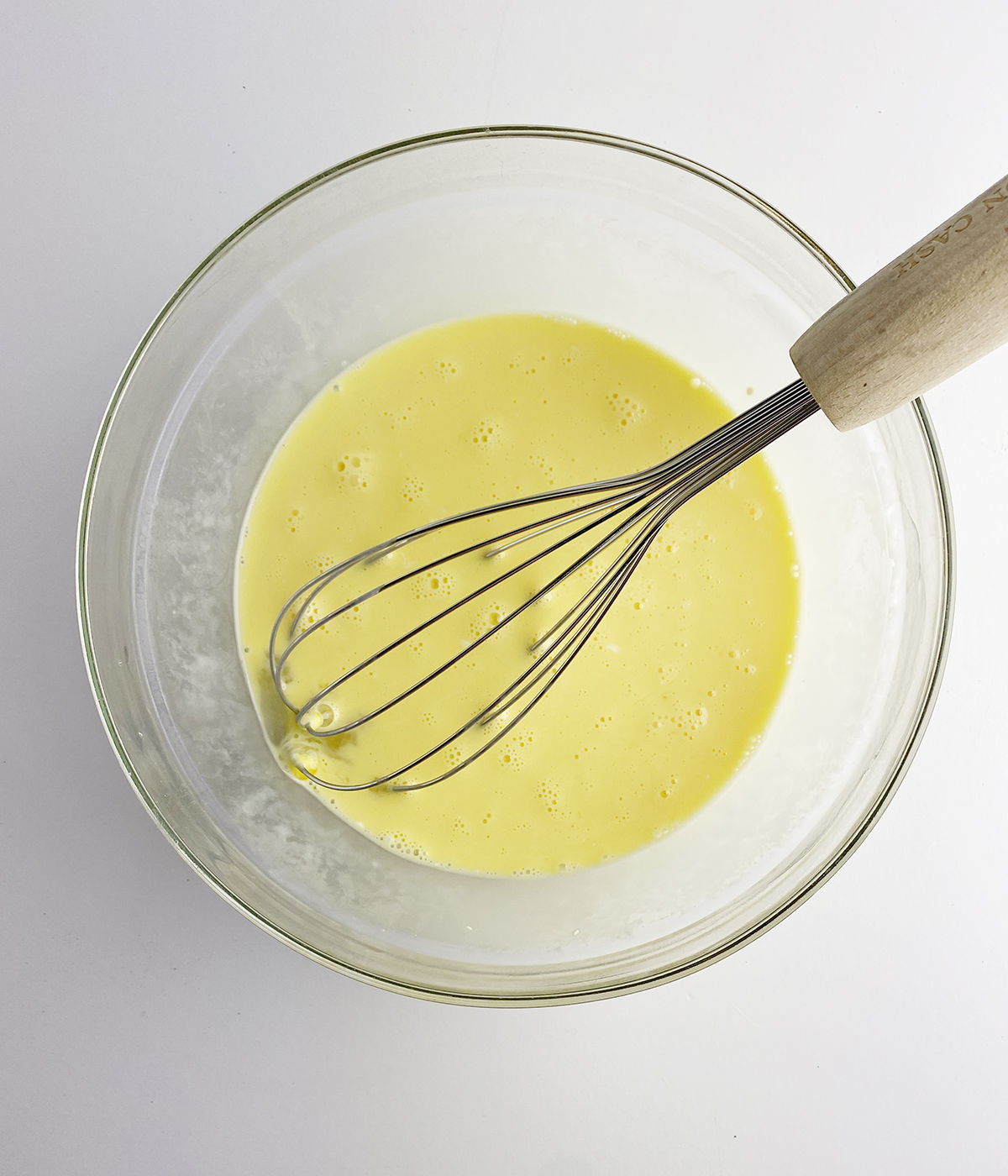 Eggs and cream whisked together in a bowl.