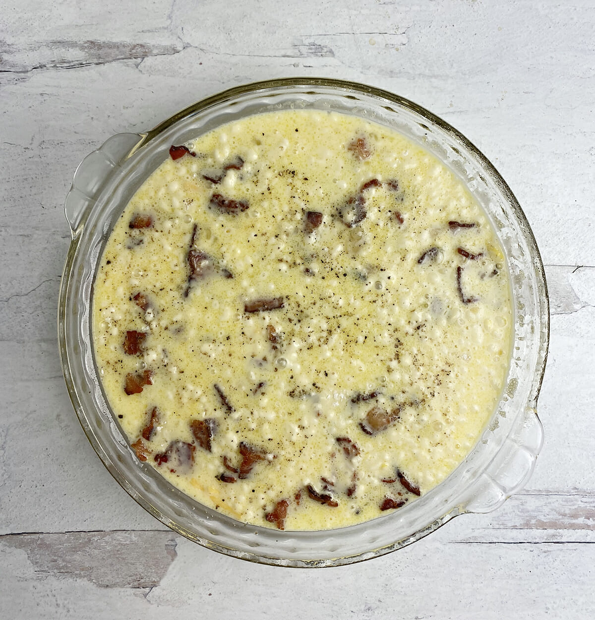 Crustless quiche in a pie plate ready for baking.