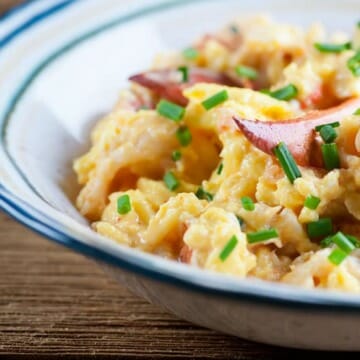 Lobster scrambled eggs in a bowl on a wooden counter.