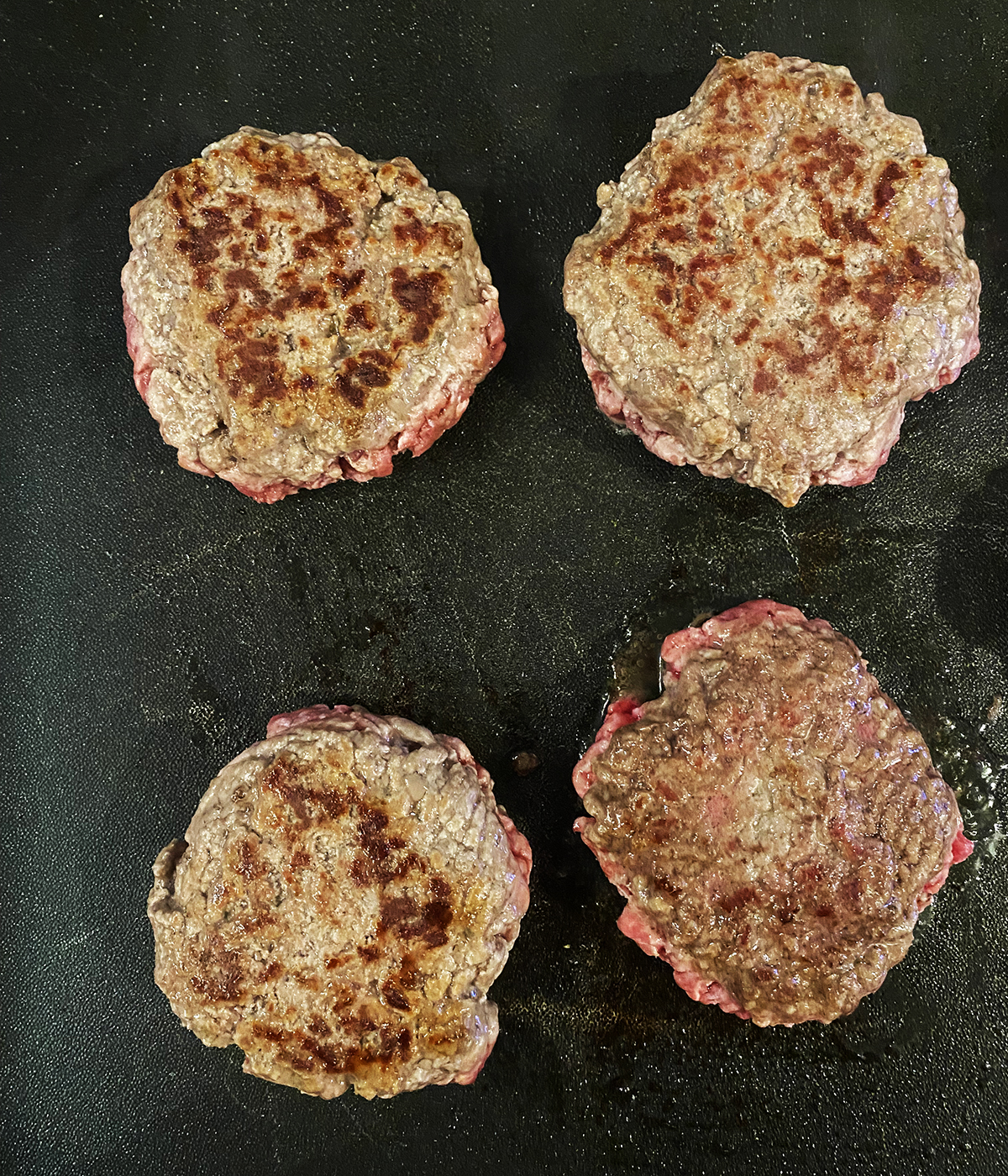 Cooked burgers on a griddle.