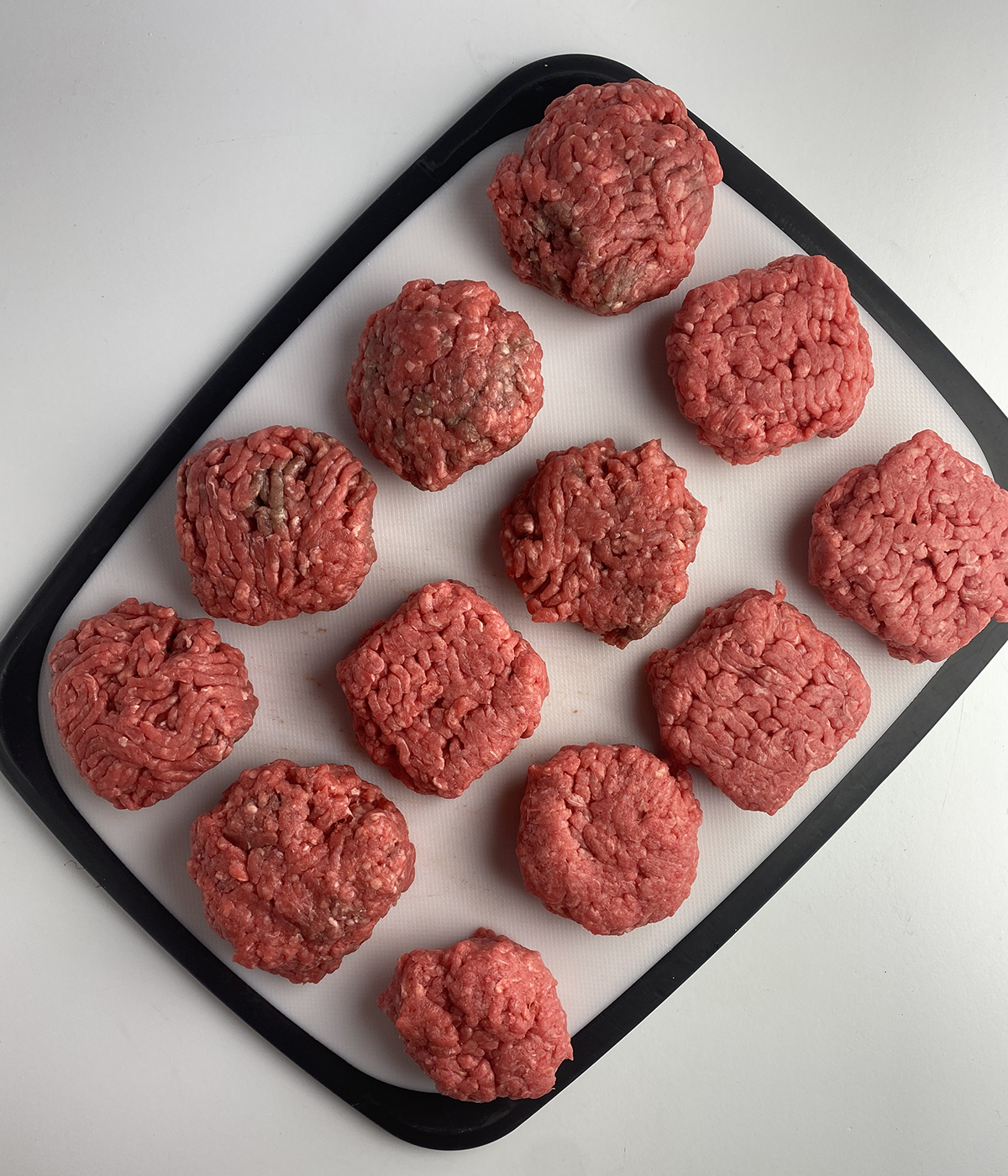 Uncooked burger patties on a cutting board.