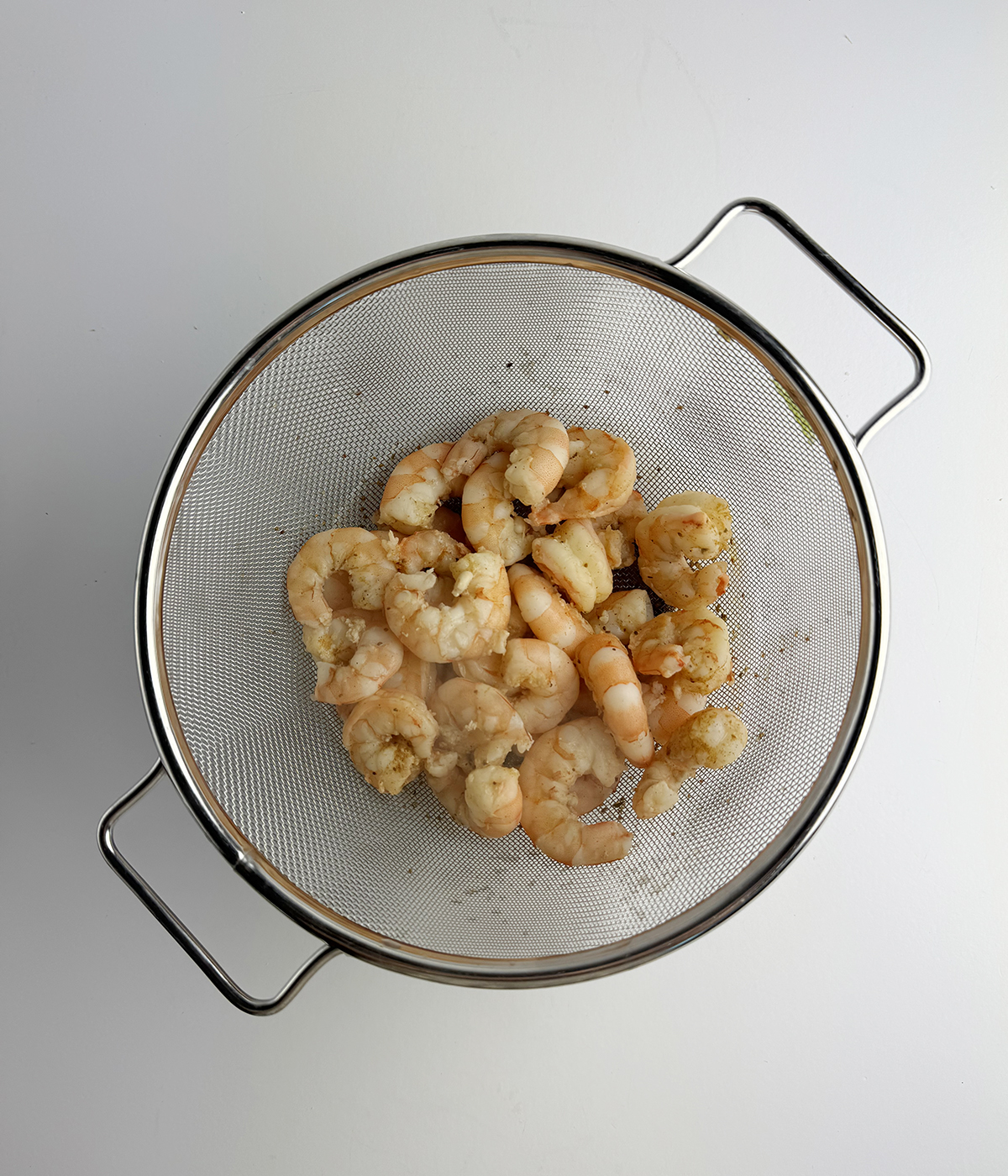 Shrimp cooked with Old Bay draining in a strainer.