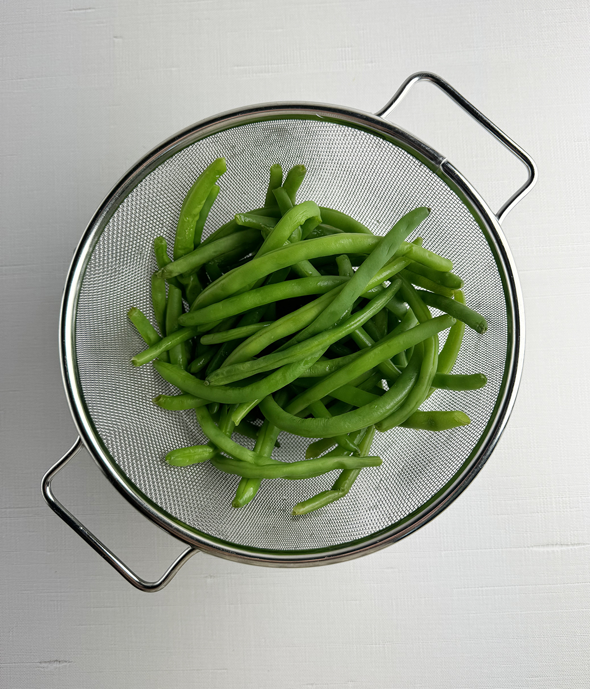 Green beans draining in a strainer.