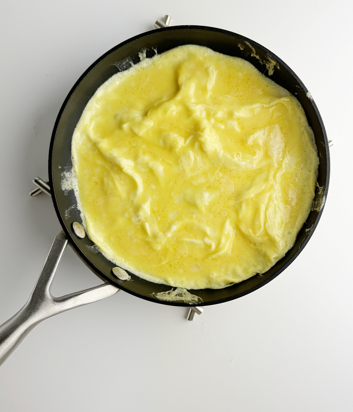 Partially cooked omelet in a skillet.