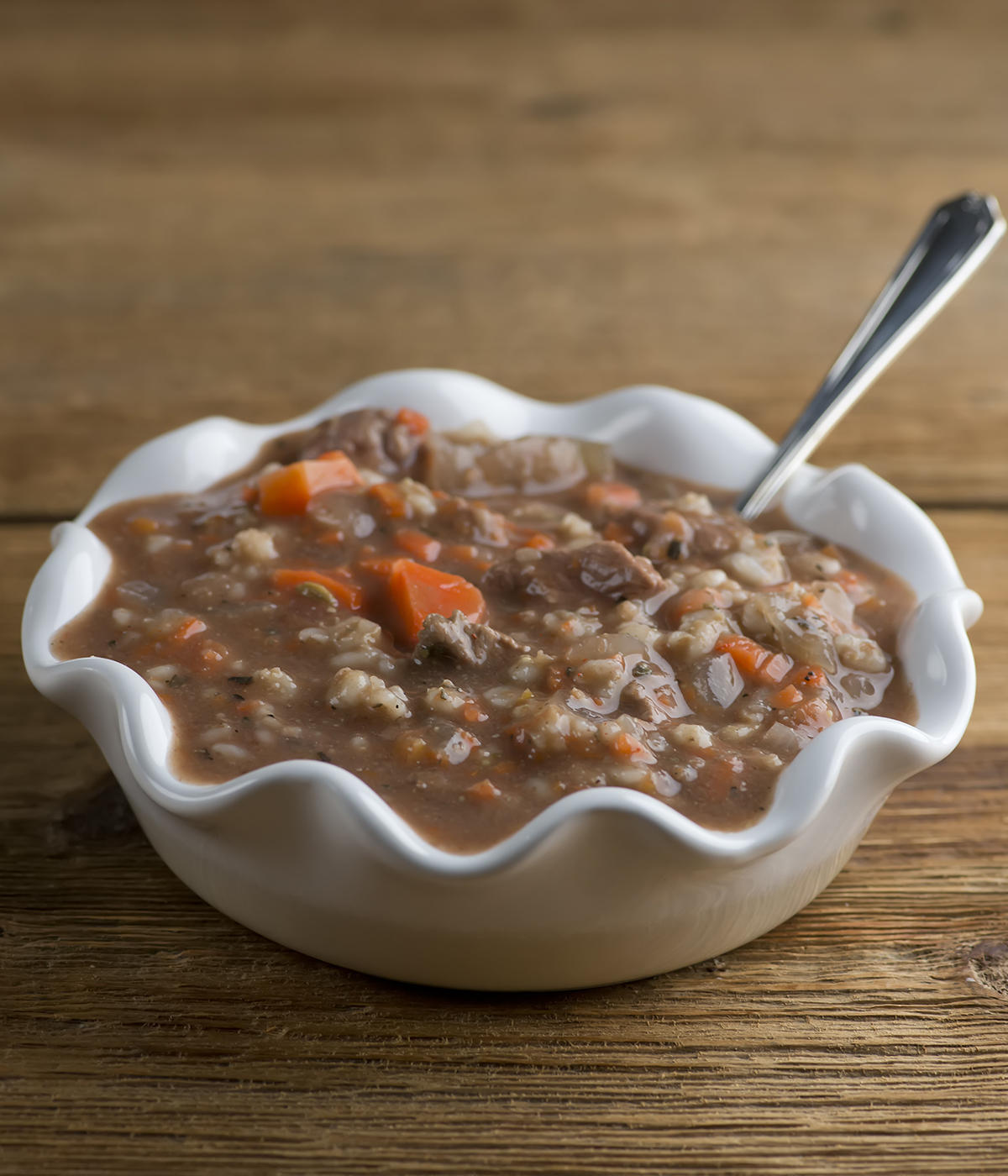 Bowl of beef barley soup with a spoon.