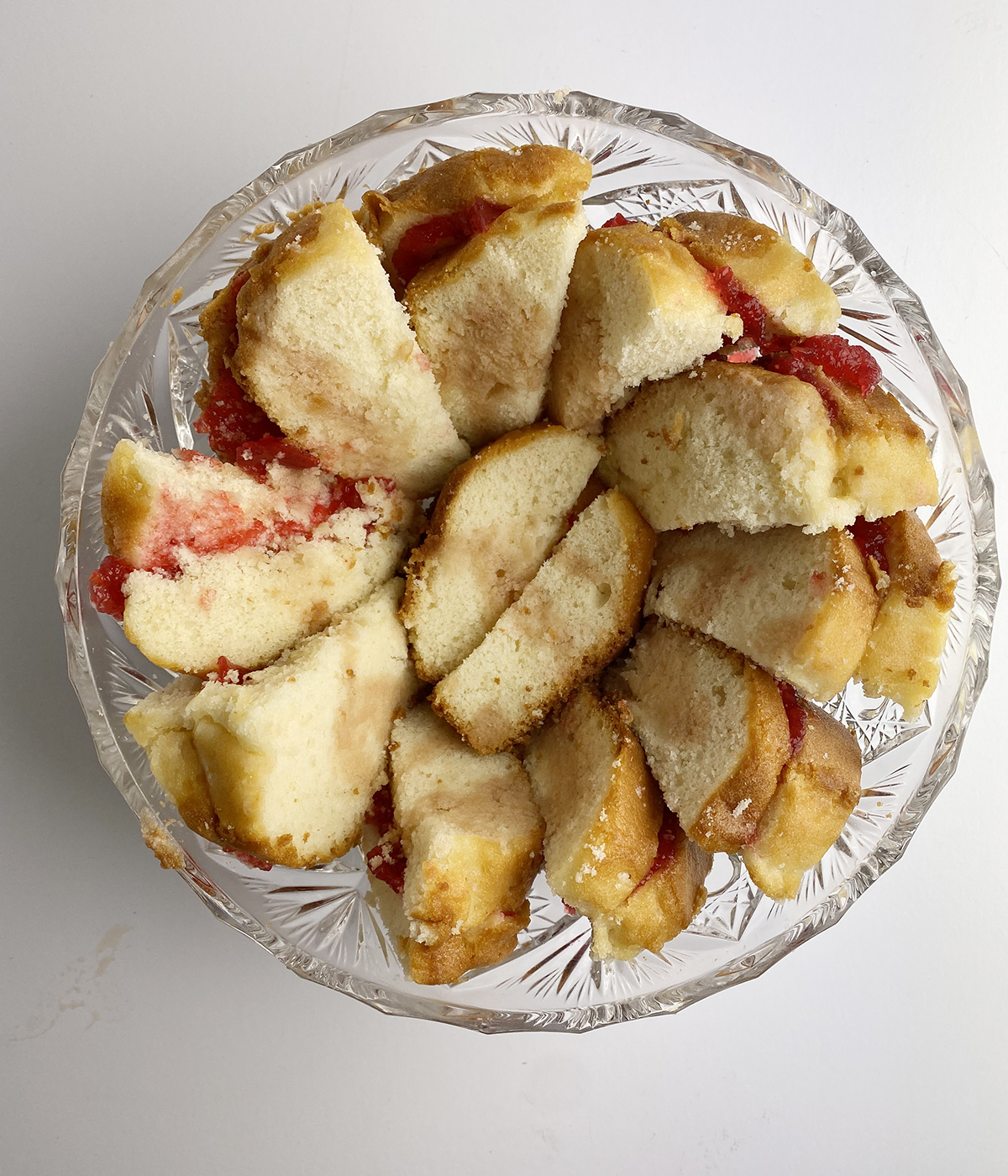 Cake and jam pieces lining a glass bowl for Irish trifle.