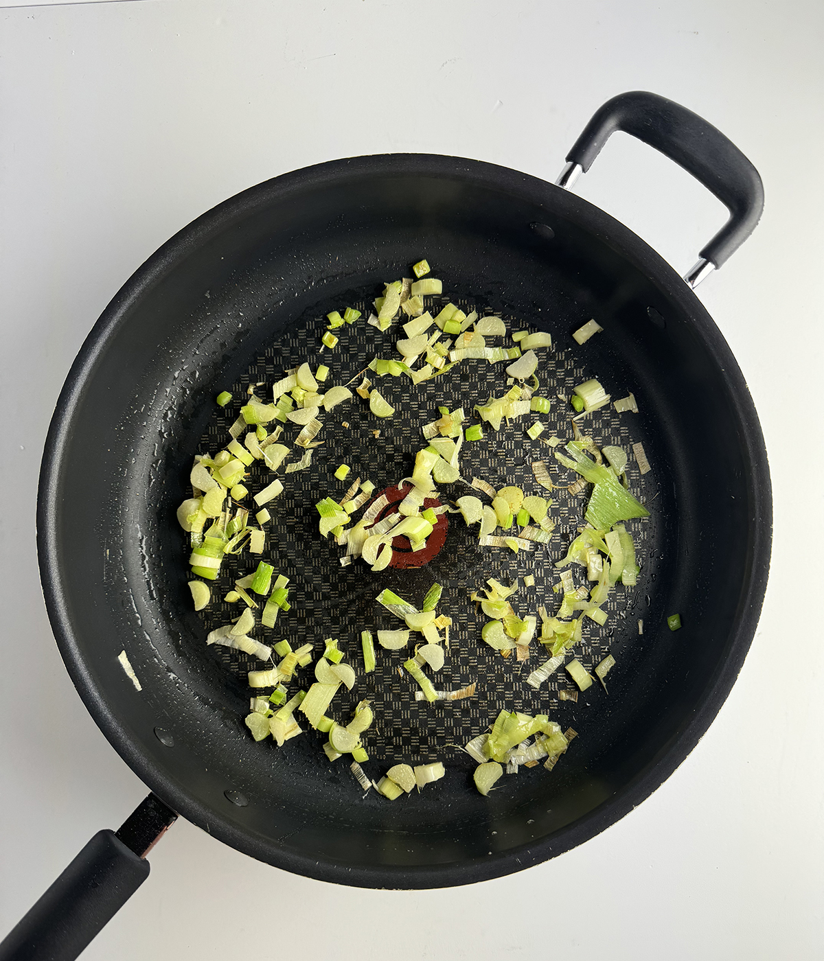 Chopped leek cooking in a skillet.