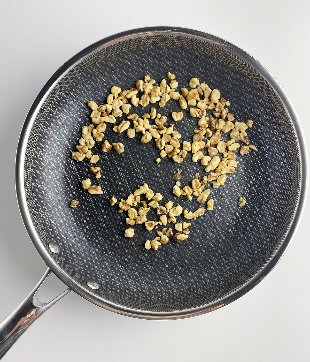 Chopped walnuts browning in a skillet.