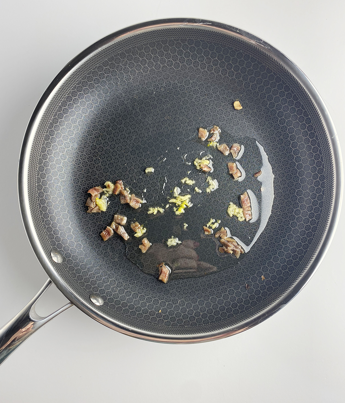 Garlic and anchovies cooking in a skillet.