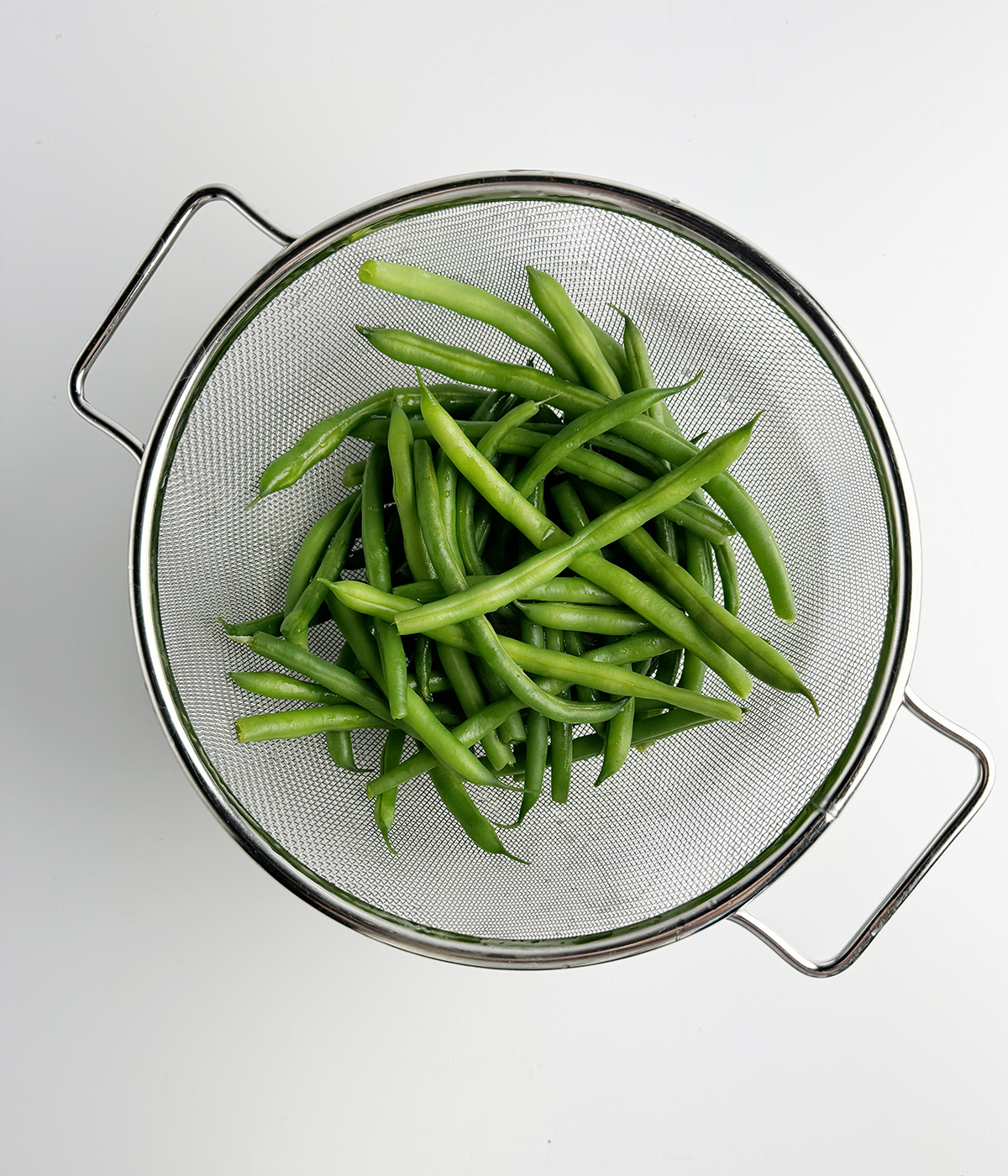 Green beans draining in a strainer.