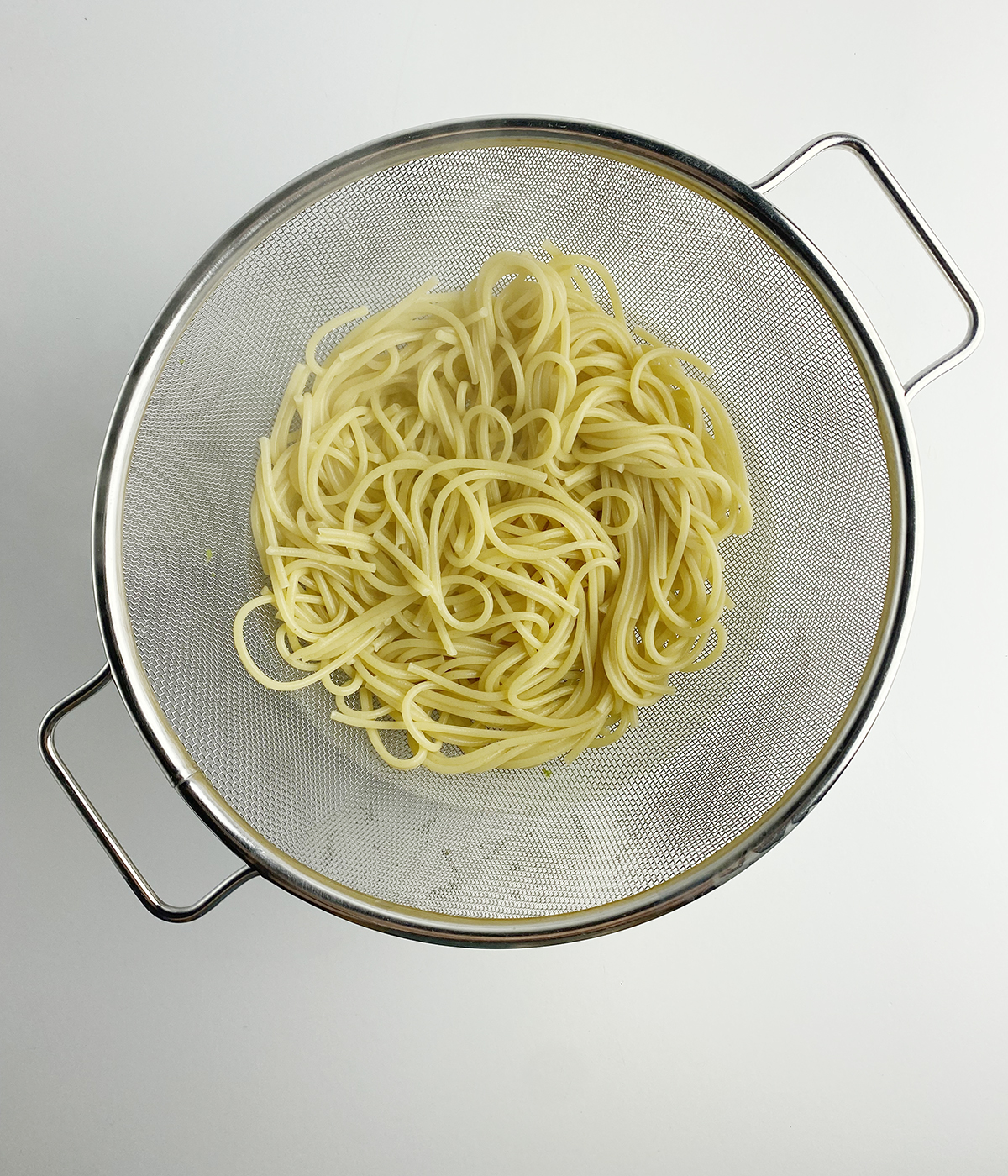 Pasta draining in a strainer.