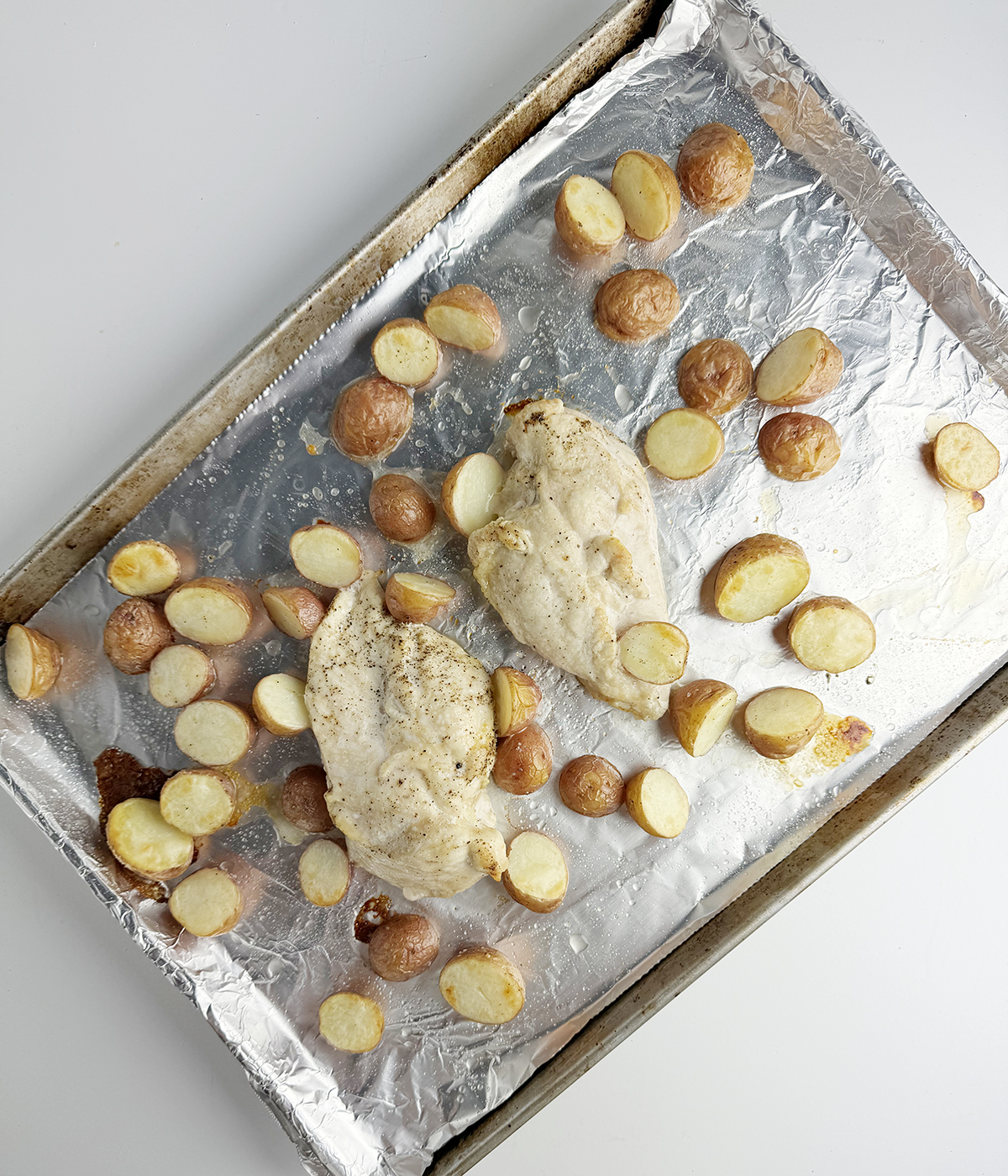 Roasted chicken and potatoes on a baking sheet.