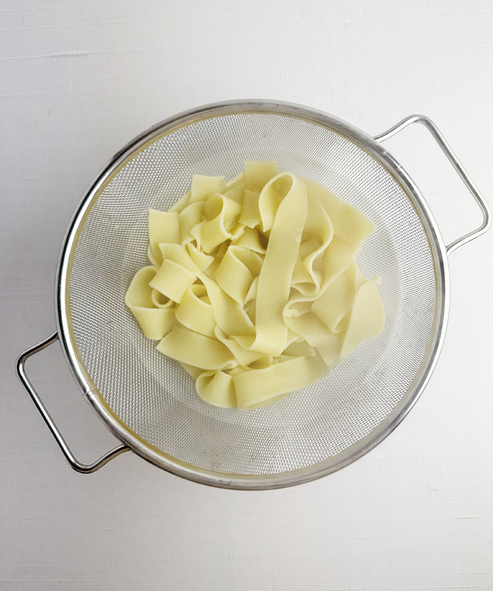 Pasta draining in a strainer.