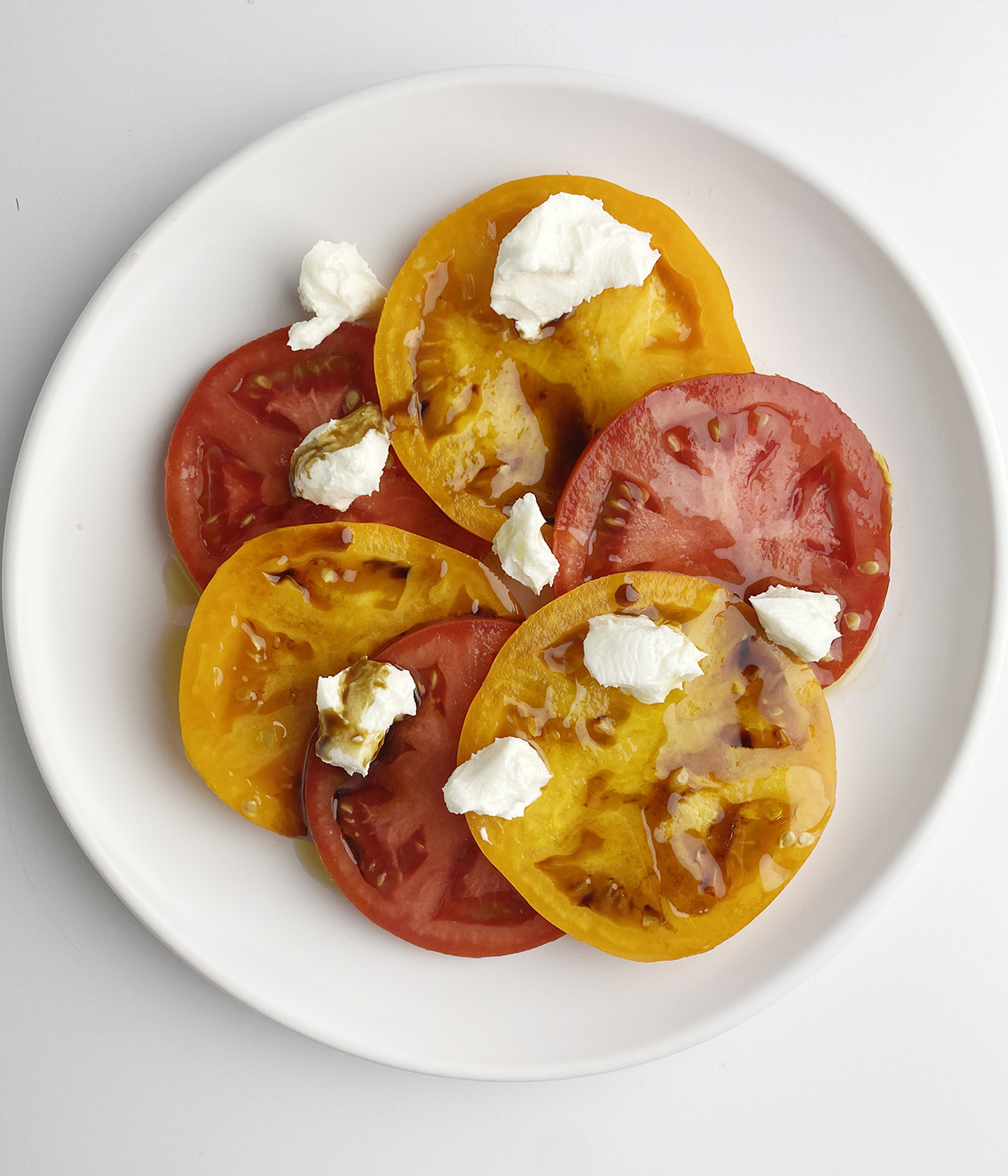 Sliced tomatoes with goat cheese on a plate.
