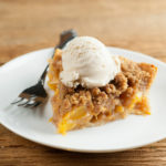 Butterscotch peach pie on a plate with a fork.