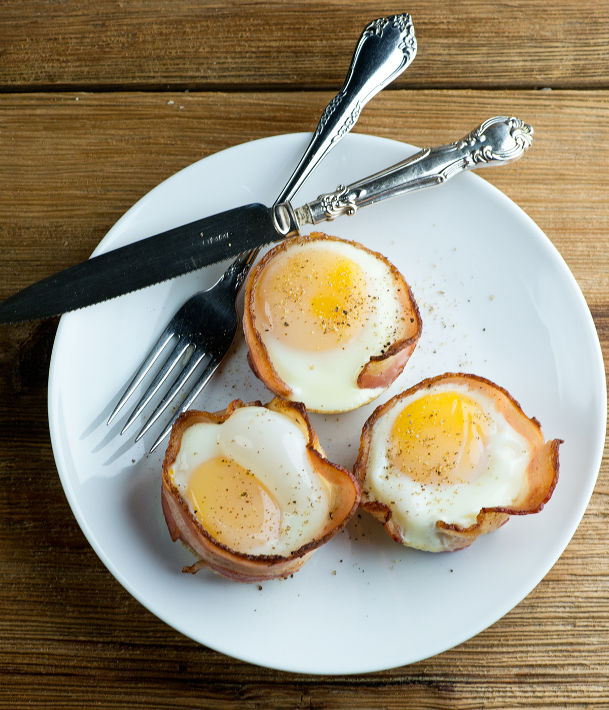 Bacon egg and cheese muffins on a plate with a knife and fork.