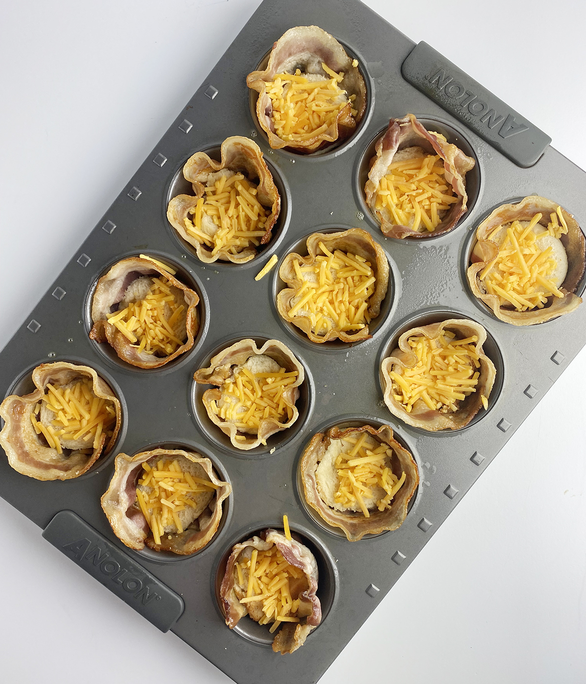 Bacon egg and cheese muffins with cheese sprinkled on top.