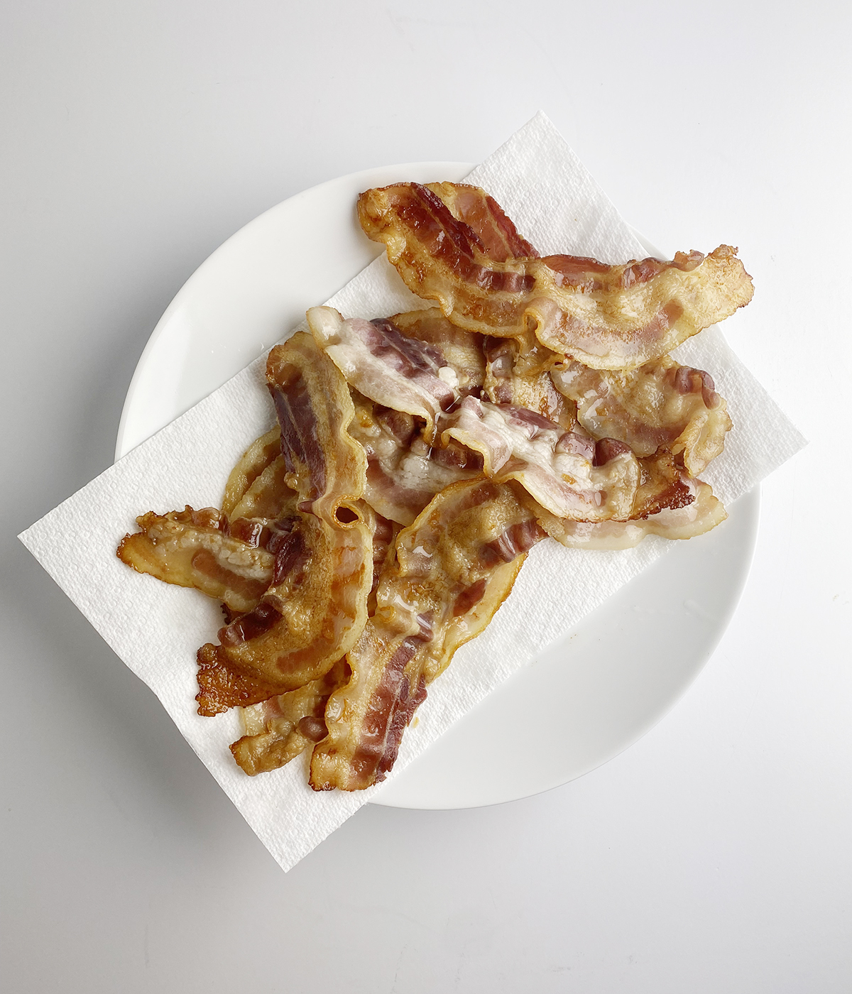 Partially cooked bacon on a plate.