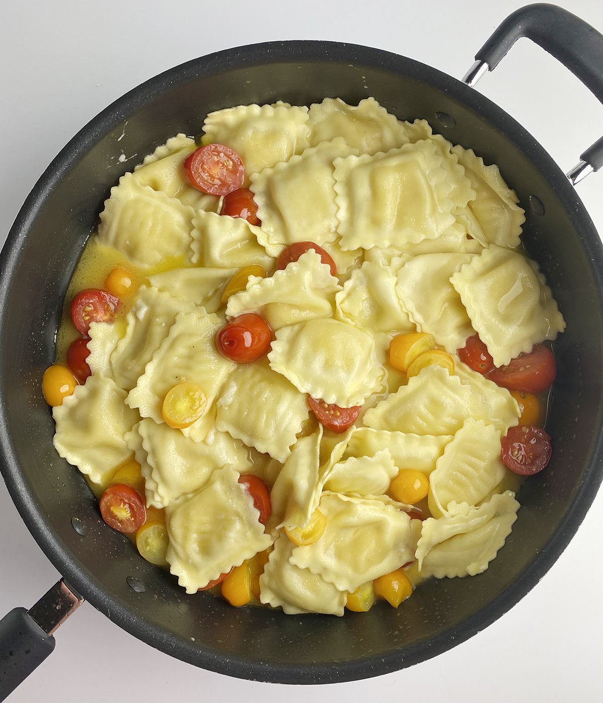 Ravioli with white wine sauce in a pan.