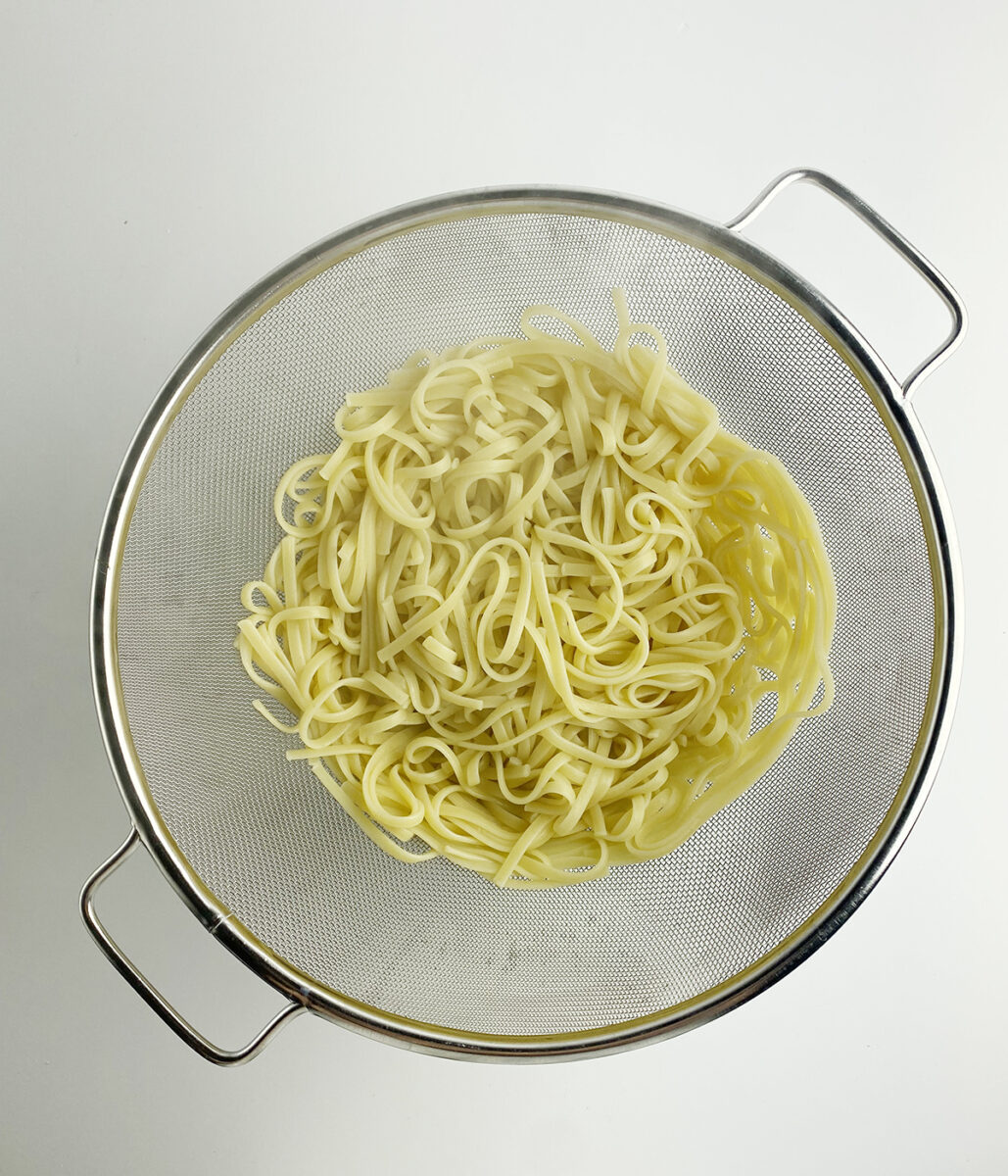 Pasta draining in a strainer.