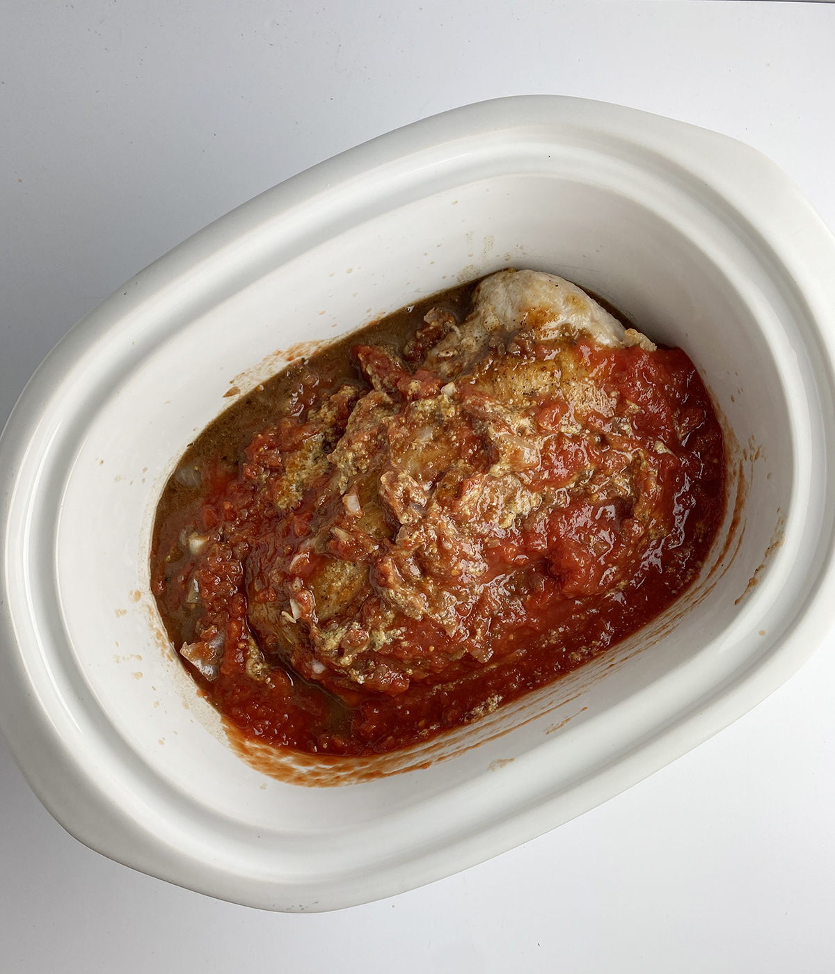 Pork in the slow cooker with tomato sauce ready to be cooked.