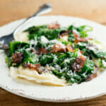 Plate of easy ravioli with baby spinach and bacon.