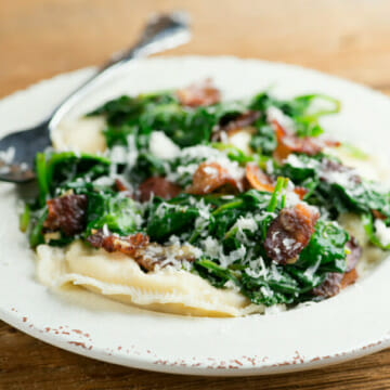 Plate of easy ravioli with baby spinach and bacon.