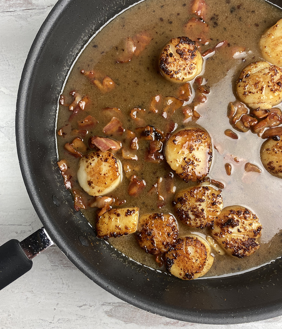 Scallops in maple cream sauce in a skillet.