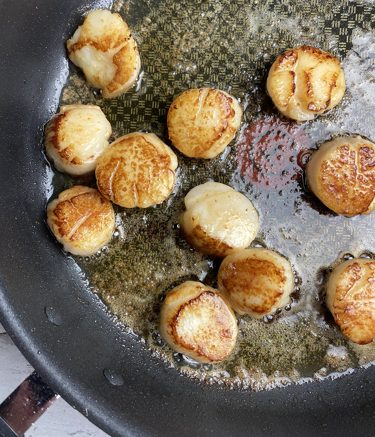 Scallops searing in a skillet.