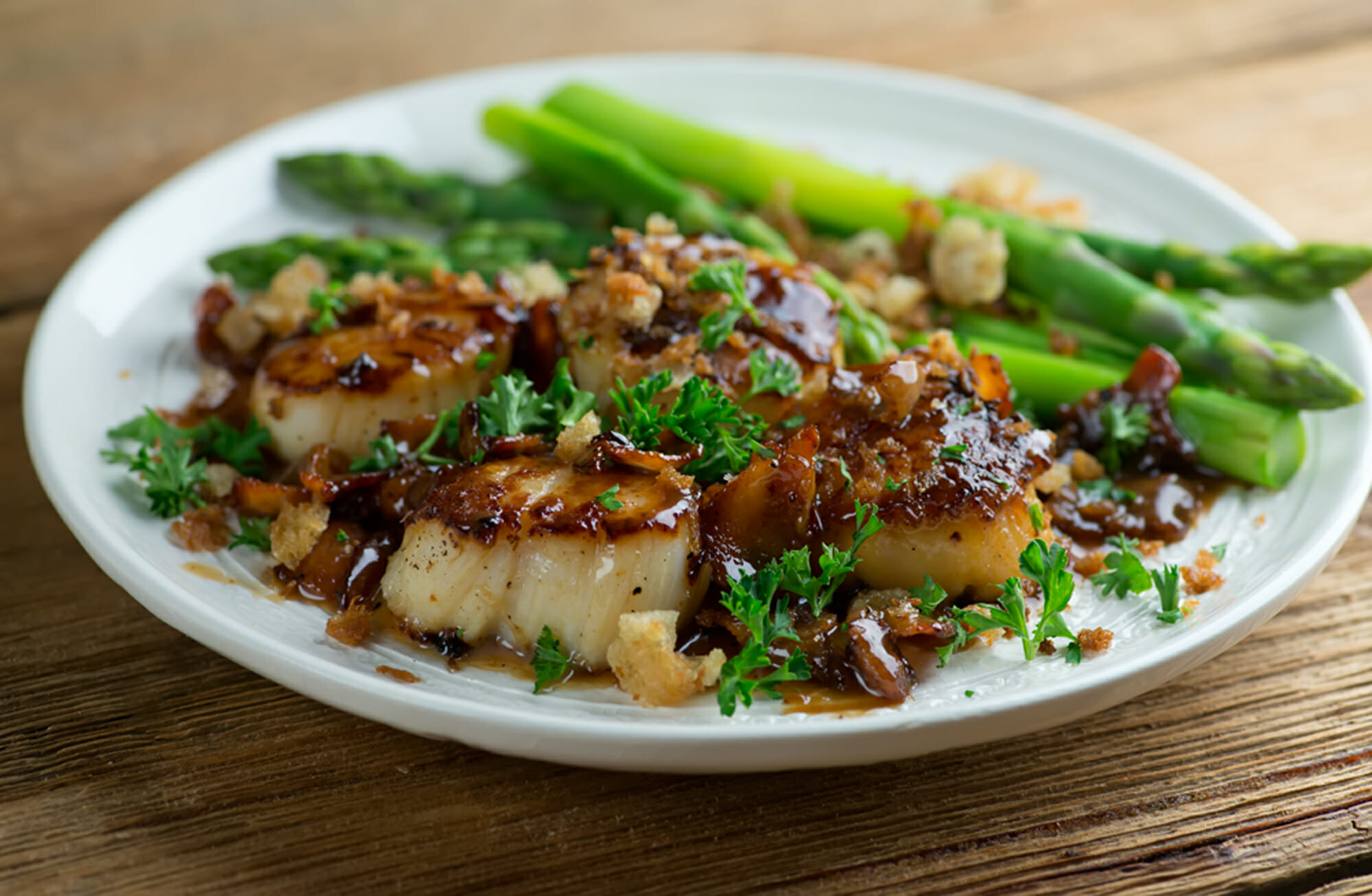 Scallops with Maple Cream Sauce on a plate with asparagus on the side.