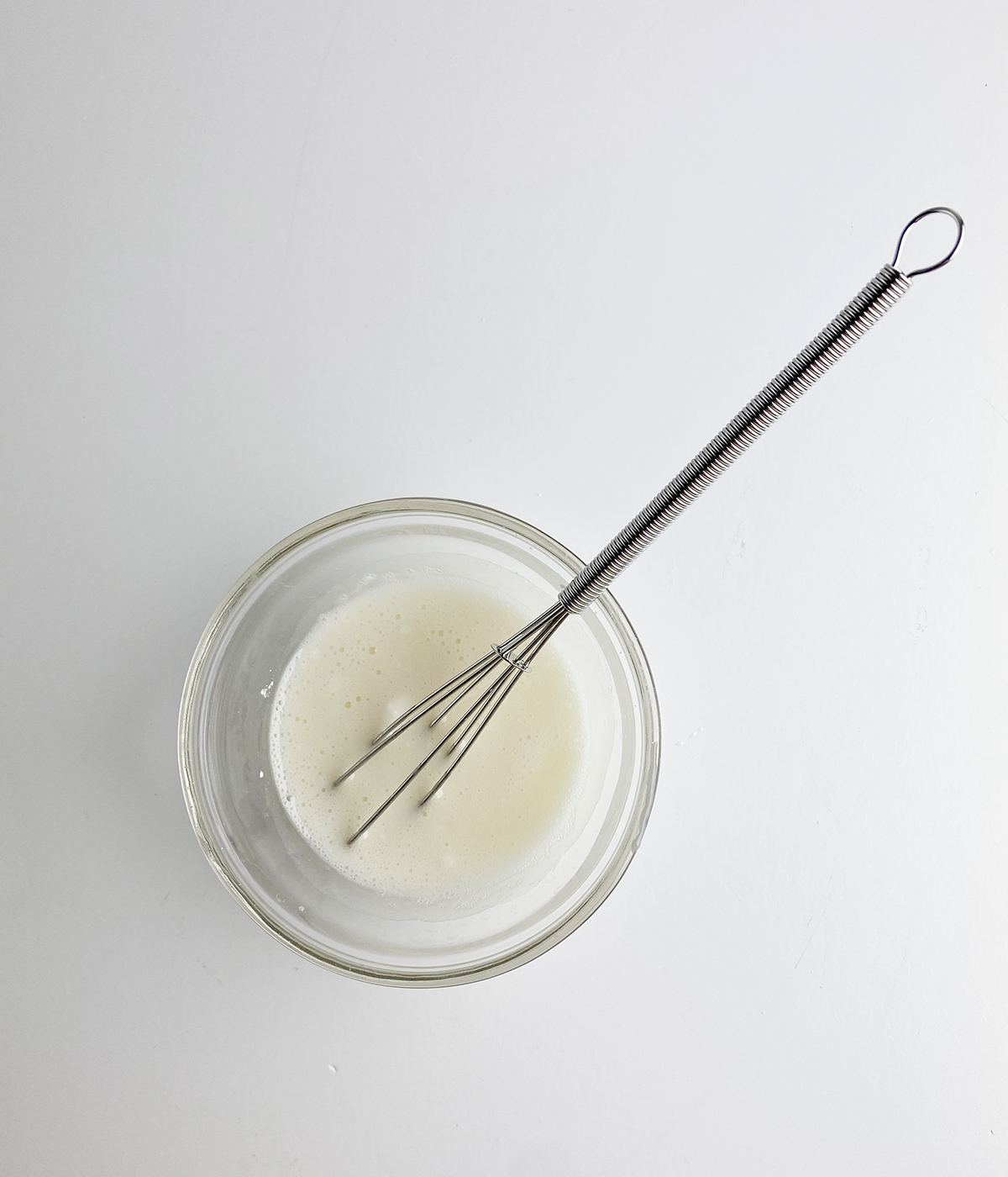 Sugar glaze in a bowl with a whisk.