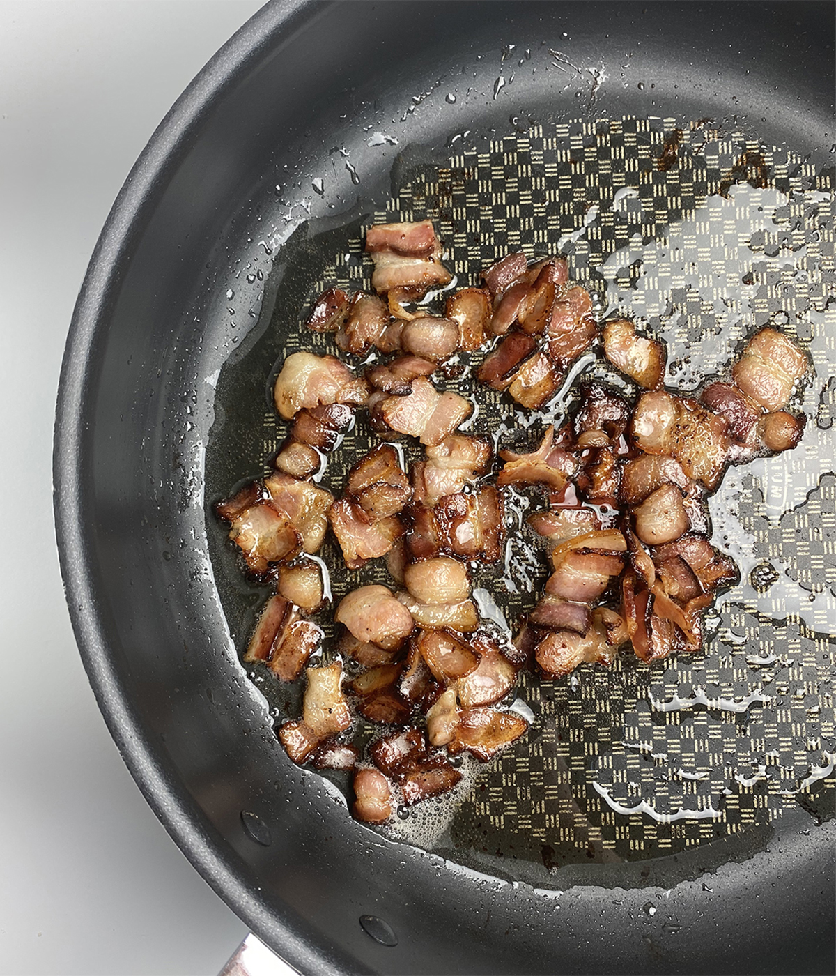 Chopped cooked bacon and drippings in a skillet.