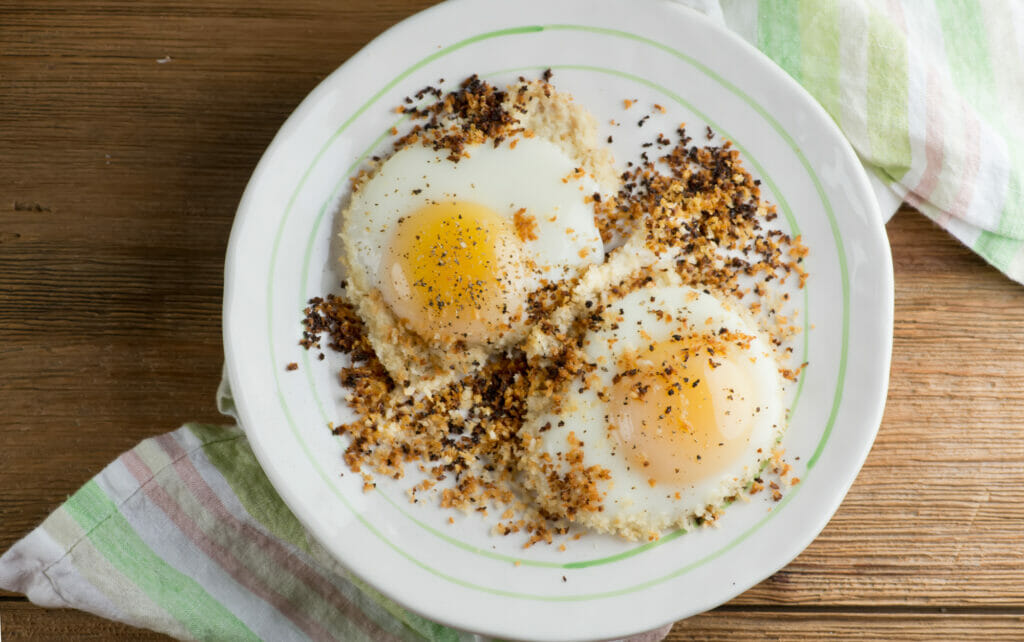 Bread crumb fried eggs on a white plate.