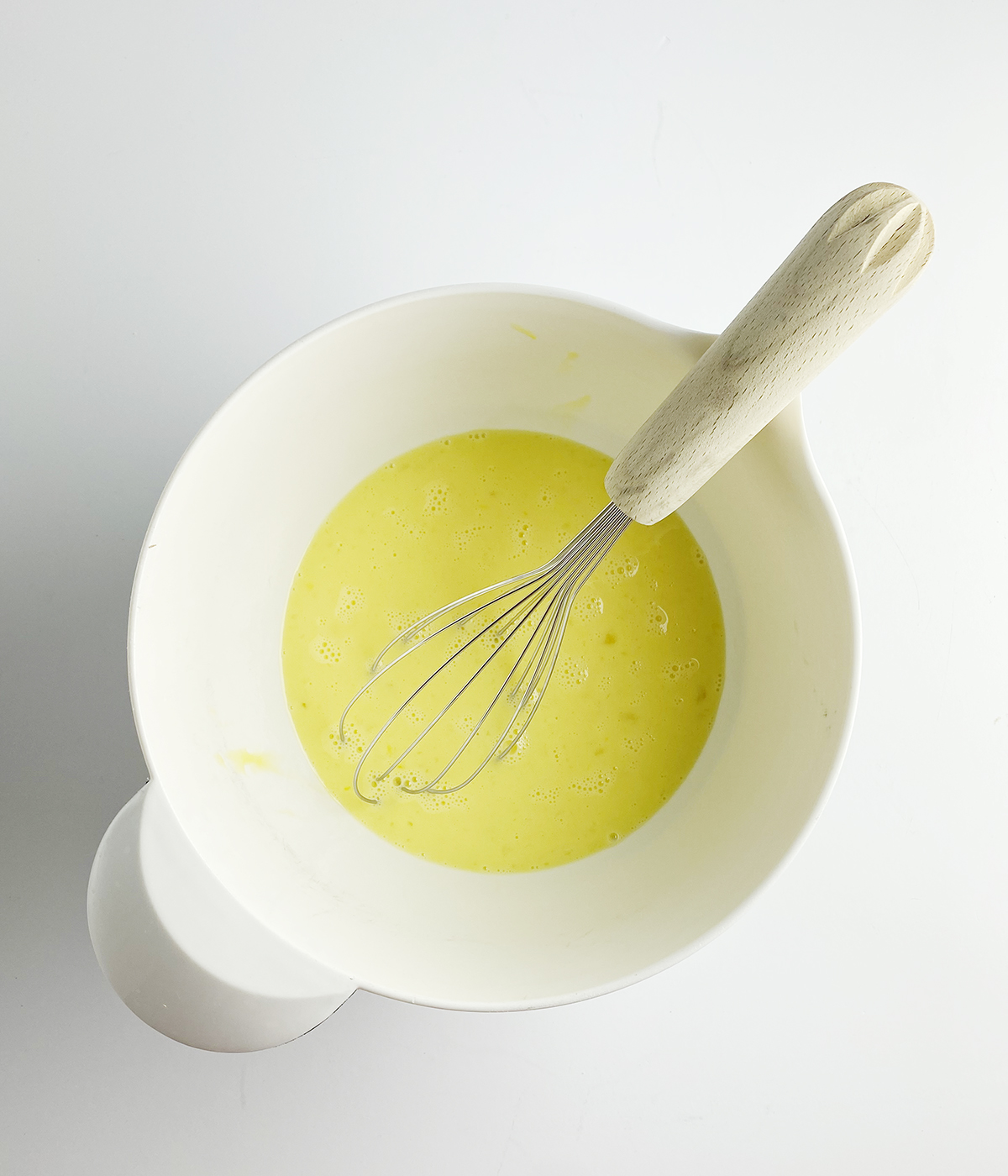 Beaten eggs in a mixing bowl with a whisk.