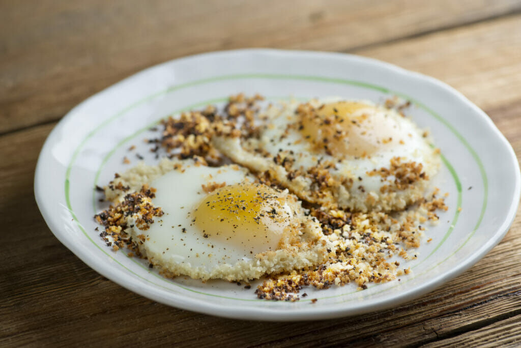 Bread crumb fried eggs on a white plate.