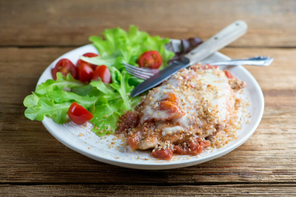 one pan chicken Parmesan One Pan Chicken Parmesan on a plate with a side salad.