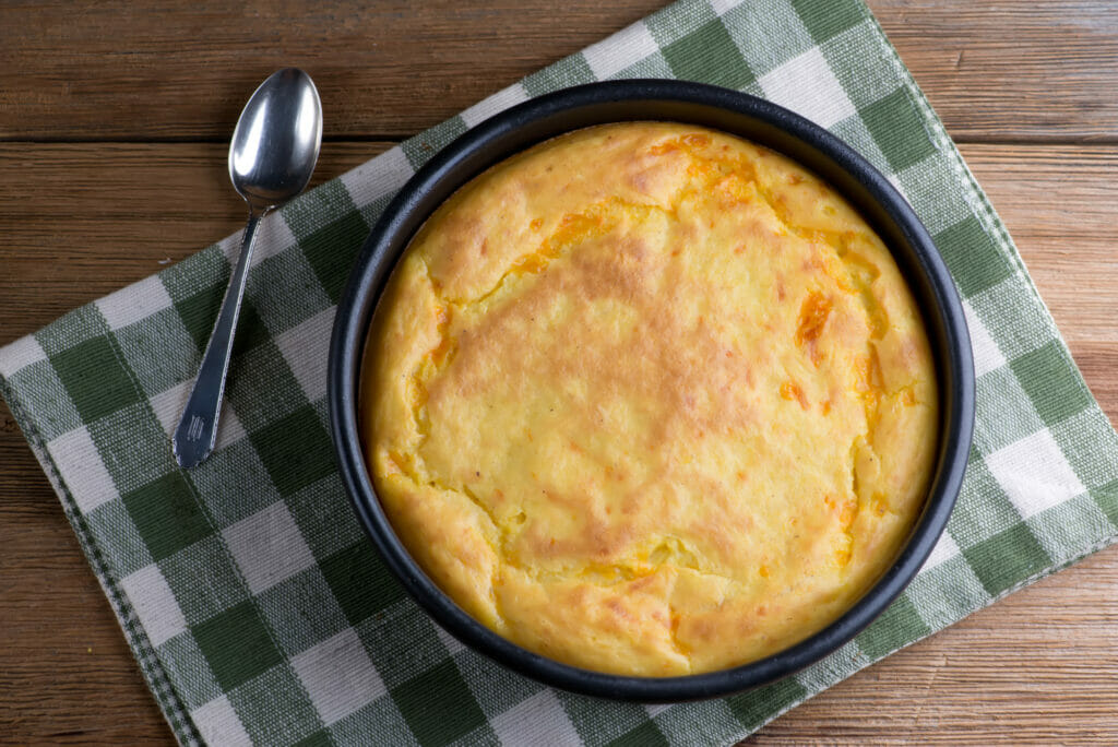 Cheesy Southern spoonbread in baking pan on a towel.