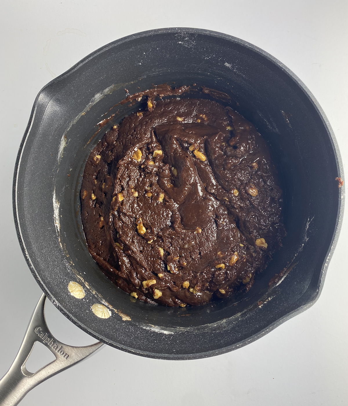Pot full of saucepan brownie batter with walnuts.