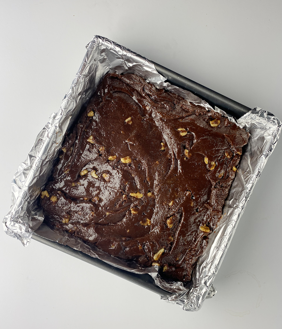 Square foil-lined pan full of saucepan brownie batter.