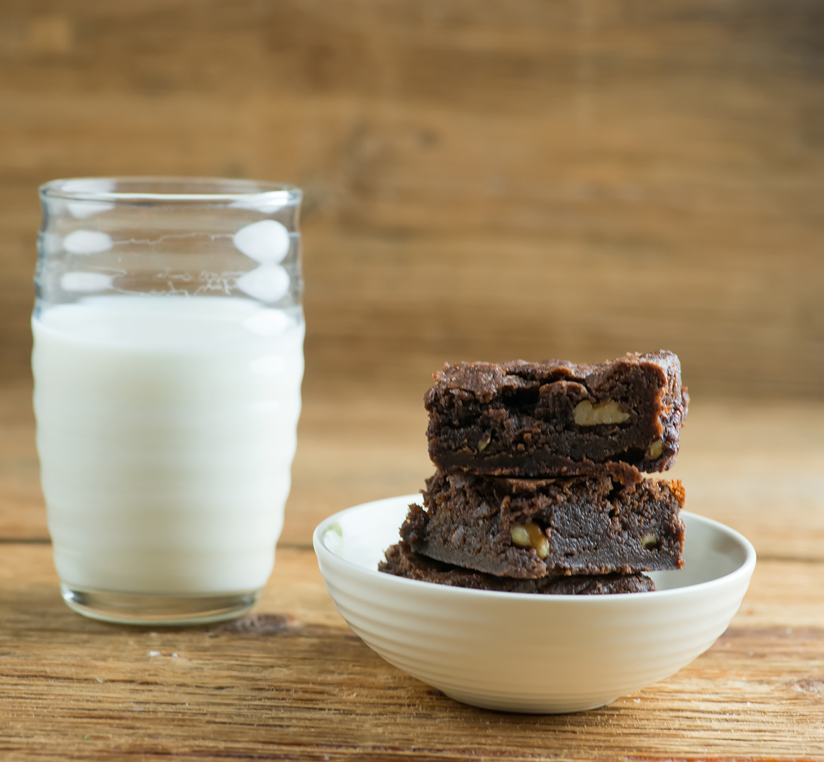 Stack of saucepan brownies with a glass of milk.